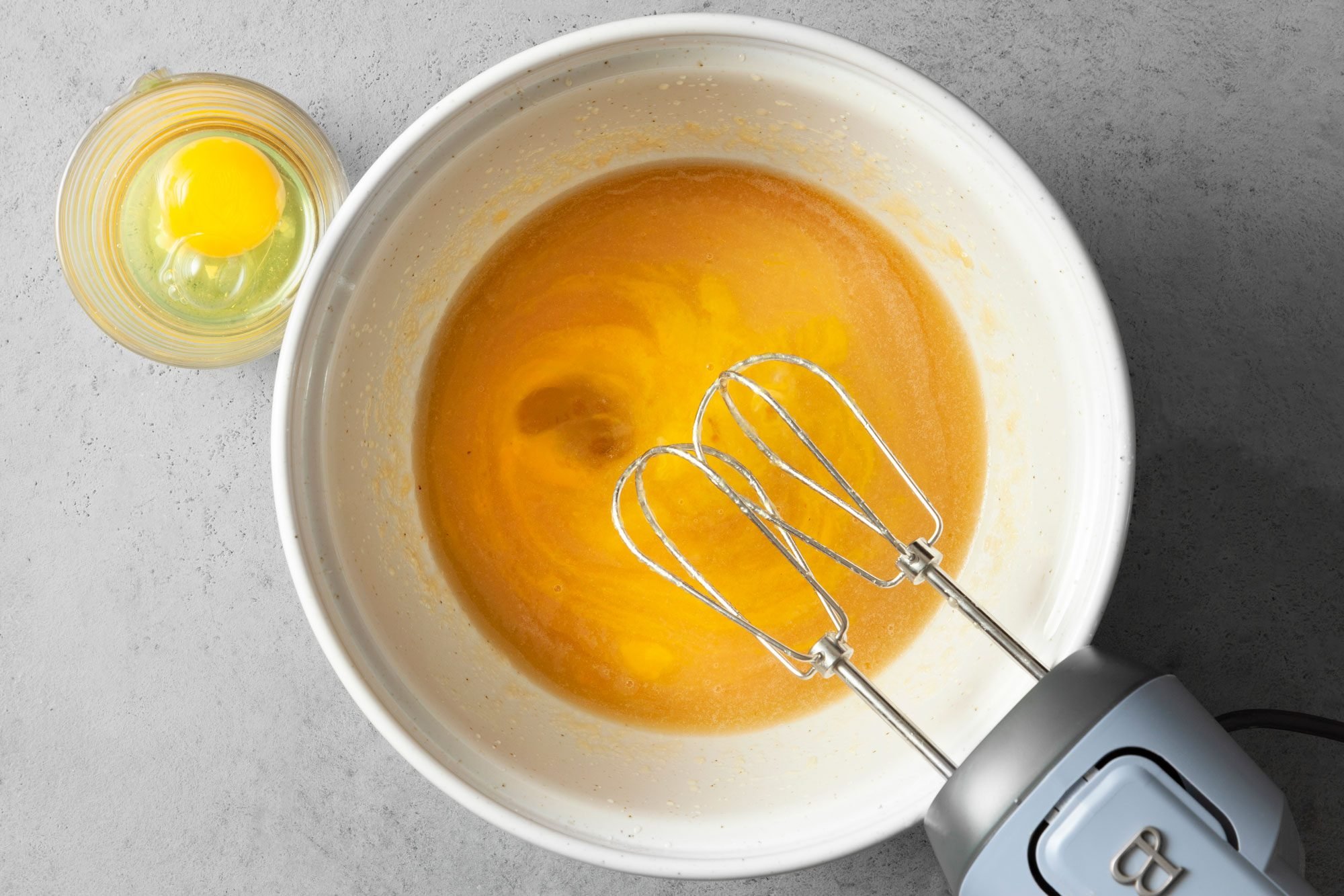 beaten eggs in a bowl; grey background; grey background;