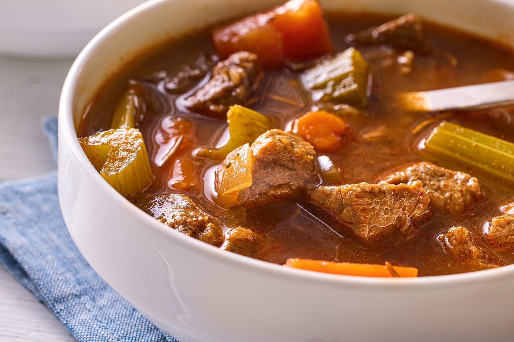 A bowl of beef stew filled with chunks of tender beef, carrots, celery, and other vegetables in a rich, brown broth. 