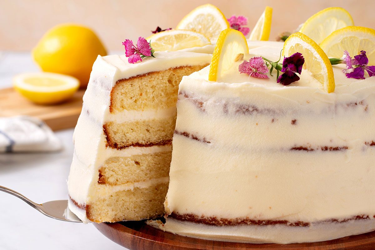 Lemon cake with slice being pulled out for Lemon Cake recipe for Taste of Home