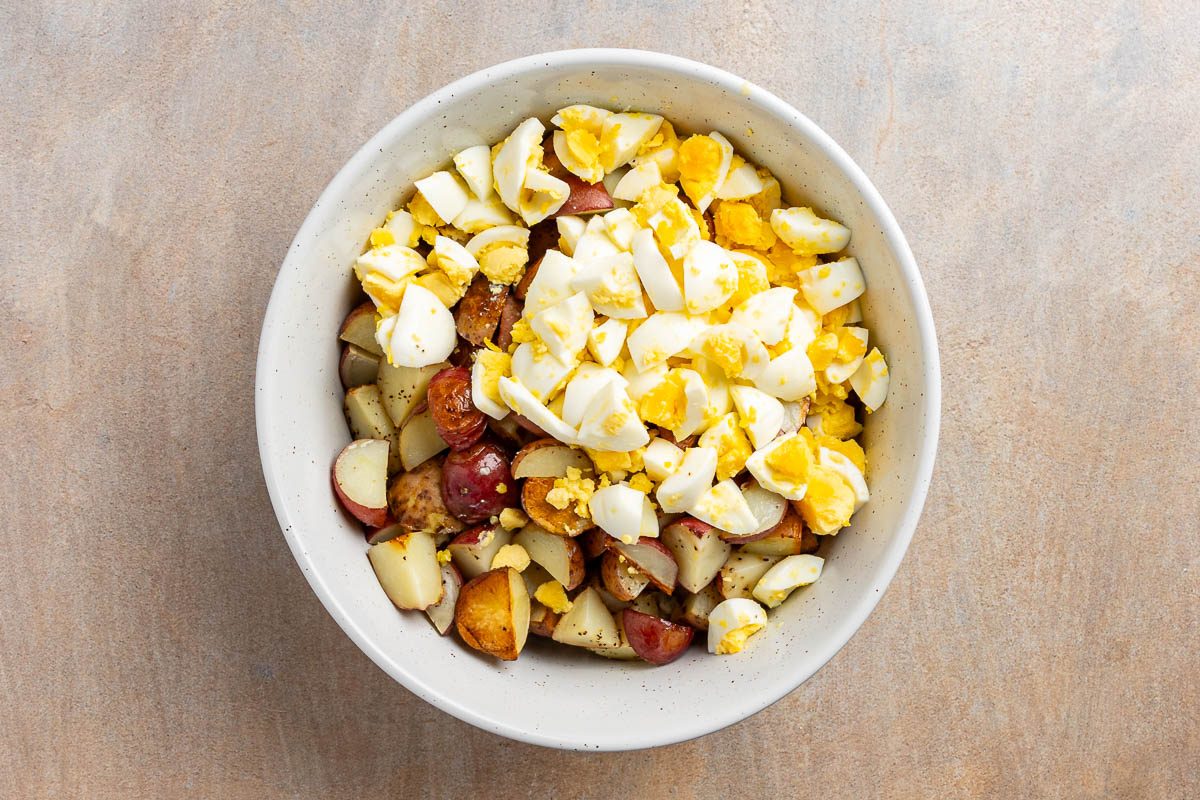 Taste Recipes Loaded Baked Potato Salad recipe photo of cooked potatoes in mixing bowl with hard boiled eggs.