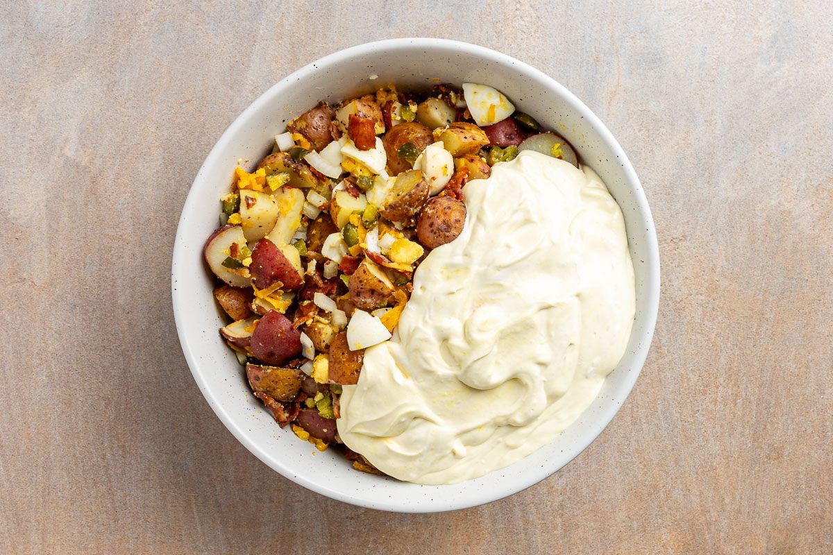 Taste Recipes Loaded Baked Potato Salad recipe photo of the dressing added to the mixture in the mixing bowl.