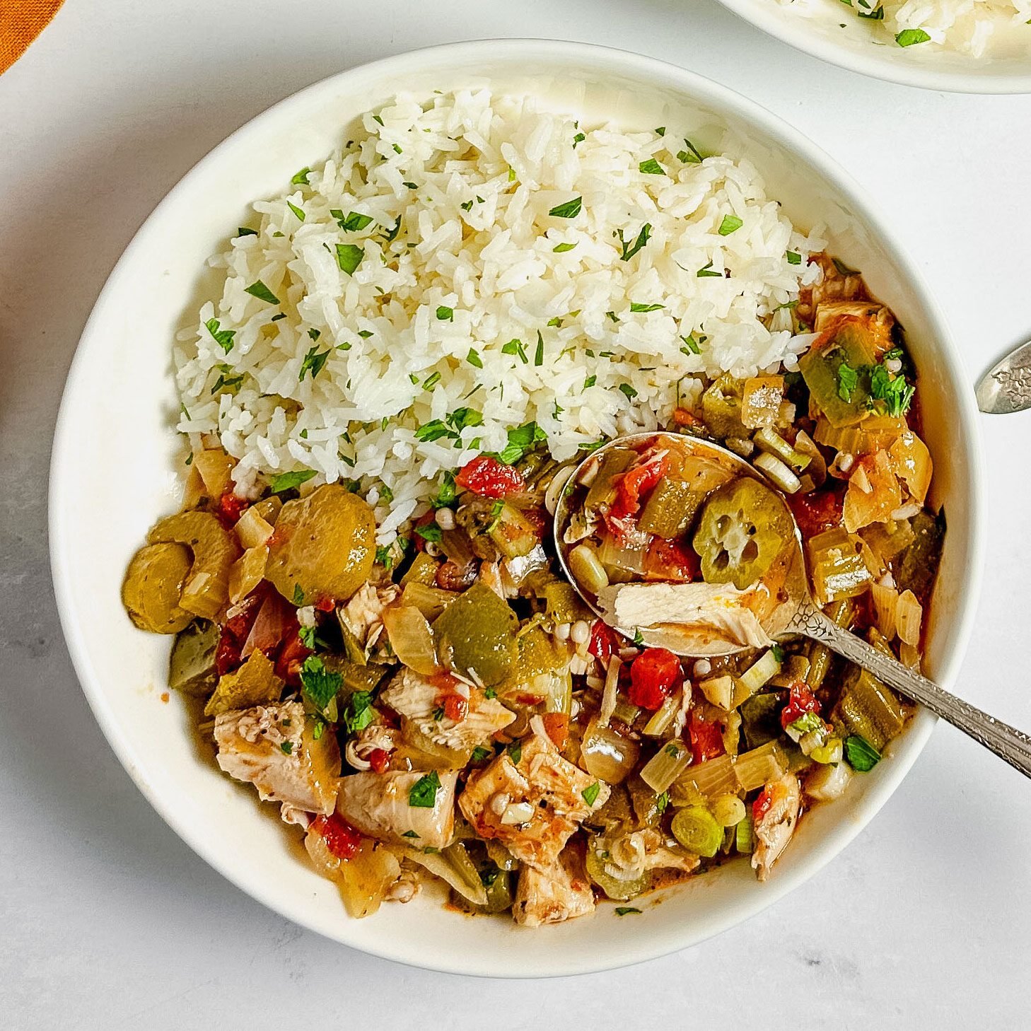 Taste of Home okra gumbo in white ceramic bowls with a linen napkin on a marble surface.