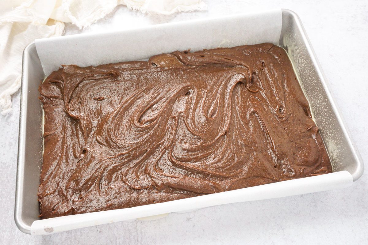 Frosted brownie batter spread in a pan ready to bake