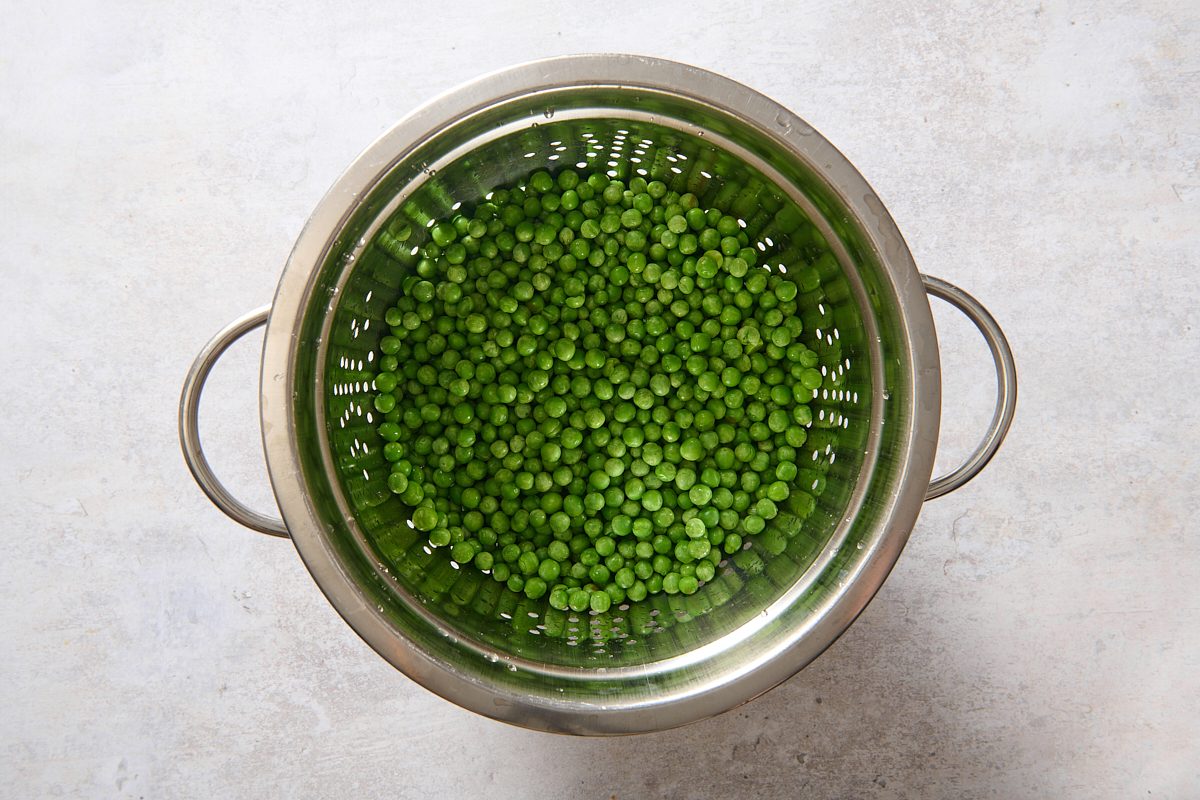 Frozen peas thawed and draining in a colander