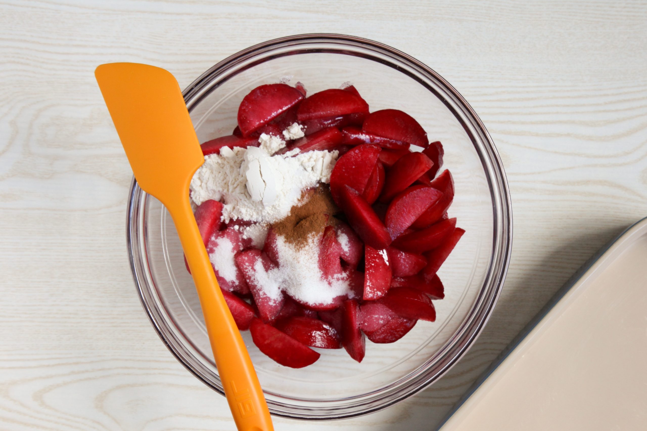 Combining the fruit and sugar for plum cobbler