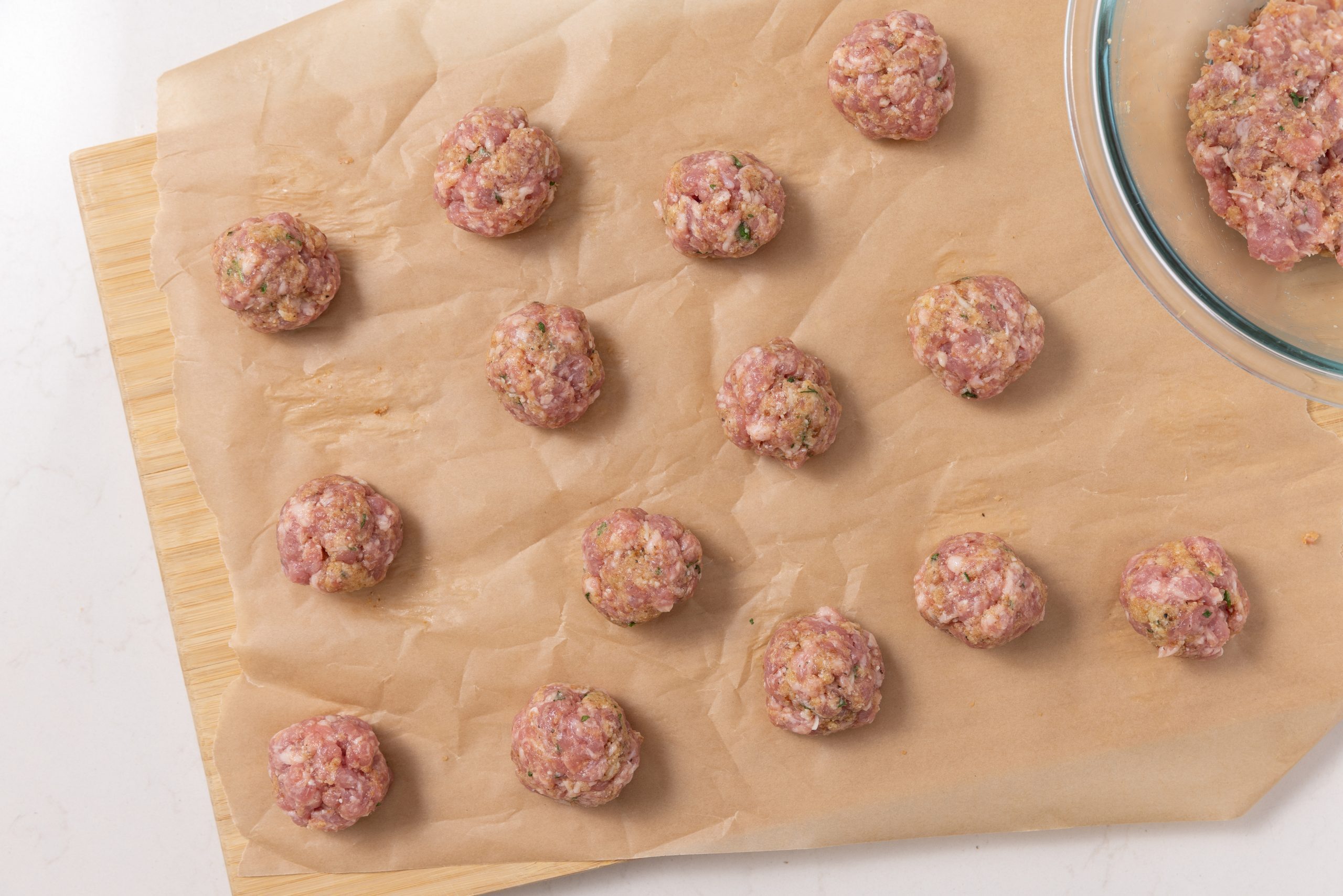 Meat mixture being shaped into meatballs.