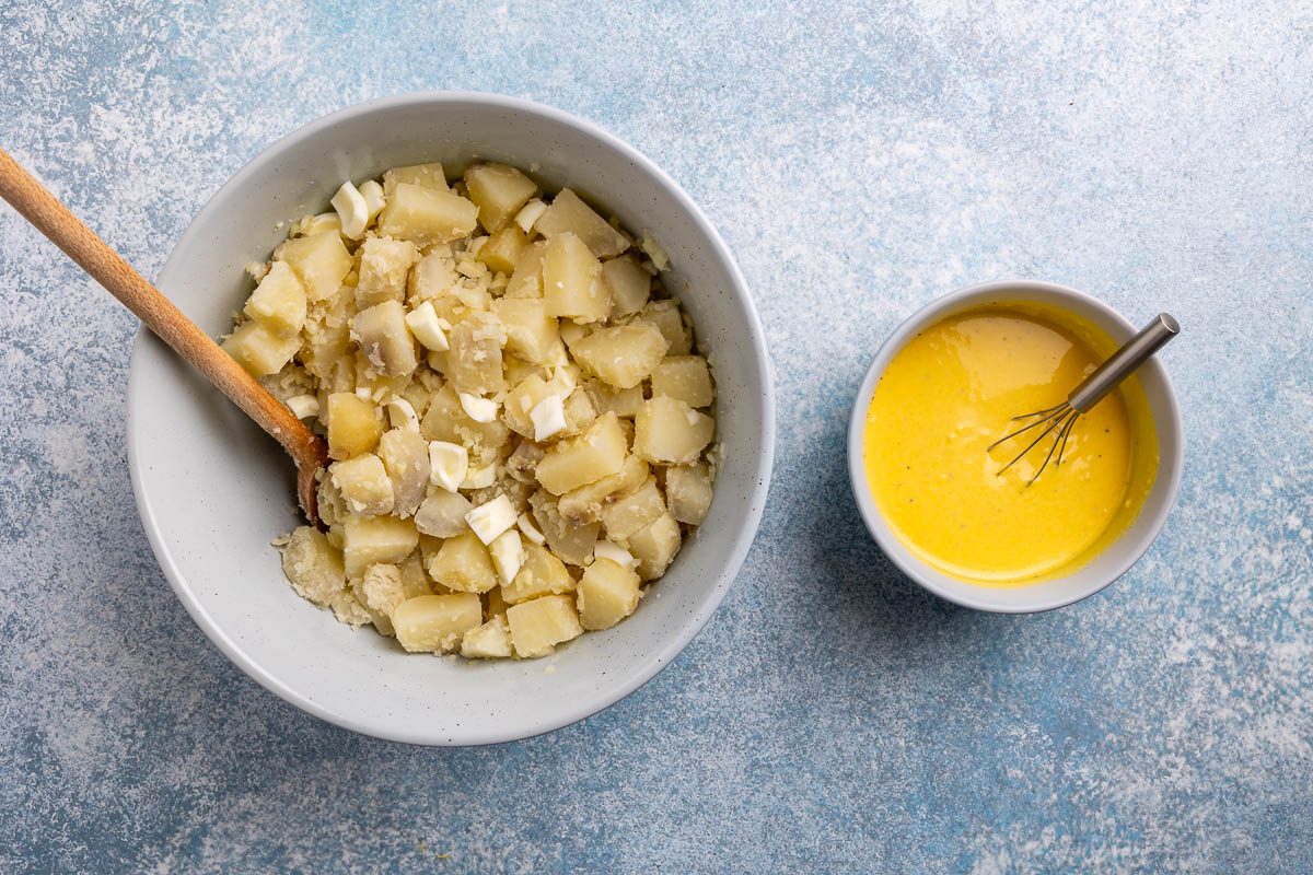 Taste of Home Potato Salad Recipe photo of egg yolks, mayo, salt, vinegar, pepper, and mustard mixed in a bowl sitting next to potato mix.