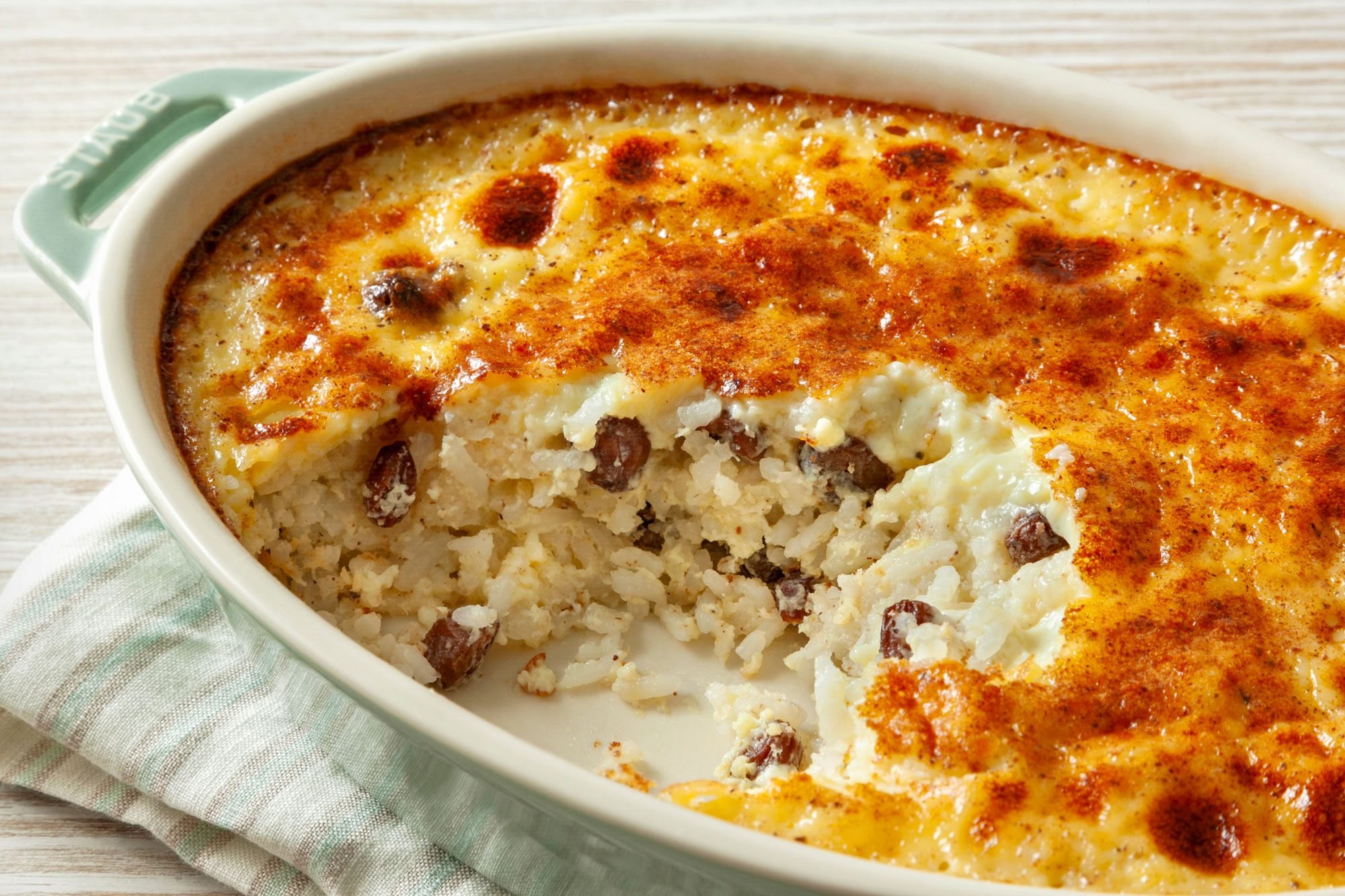 3/4th shot; wooden background; Grandma's Rice Pudding in an oval dish over kitchen napkin;