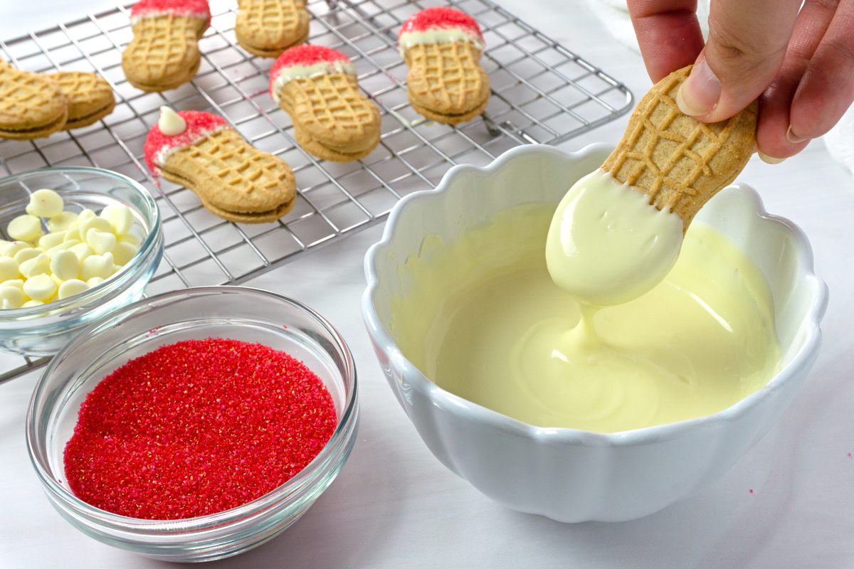 Dipping a nutter butter cookie into melted white chocolate to make Santa Claus cookies for Taste of Home RMS 21624