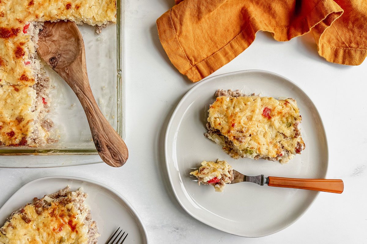 Taste of Home sausage hashbrown breakfast casserole on white plates on a marble surface.