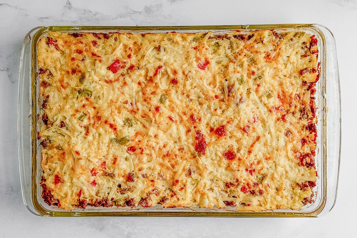 Taste of Home sausage hashbrown breakfast casserole in a glass baking dish on a marble surface.