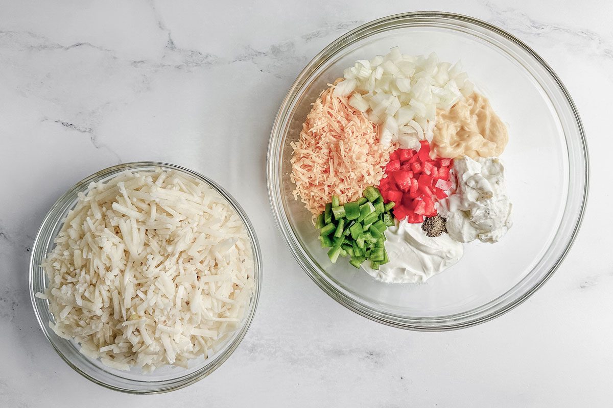 Ingredients for Taste of Home sausage hashbrown breakfast casserole in glass bowls on a marble surface.