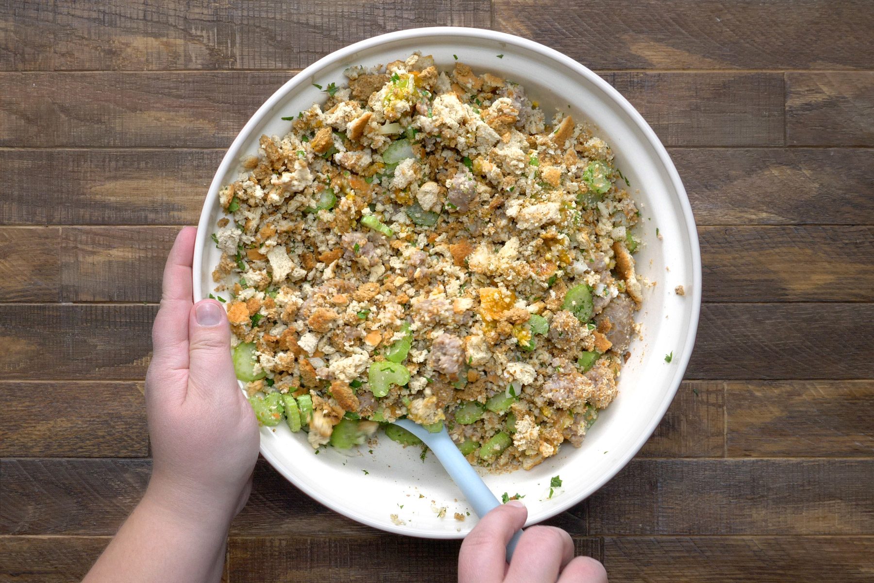 sausage, celery mixture, milk, bread cubes, eggs, parsley, salt and pepper mixed in a bowl.