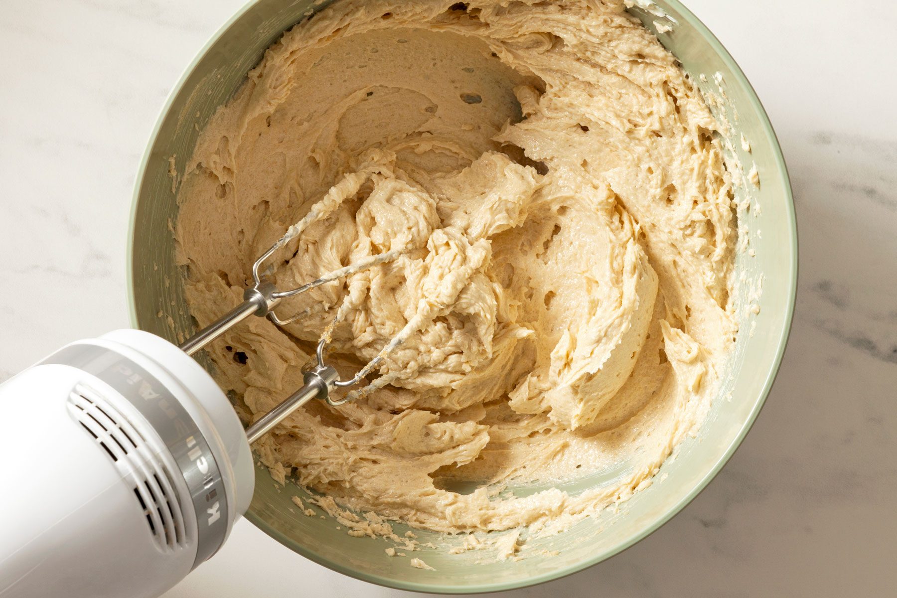 Butter and sugar being mixed in a large bowl.