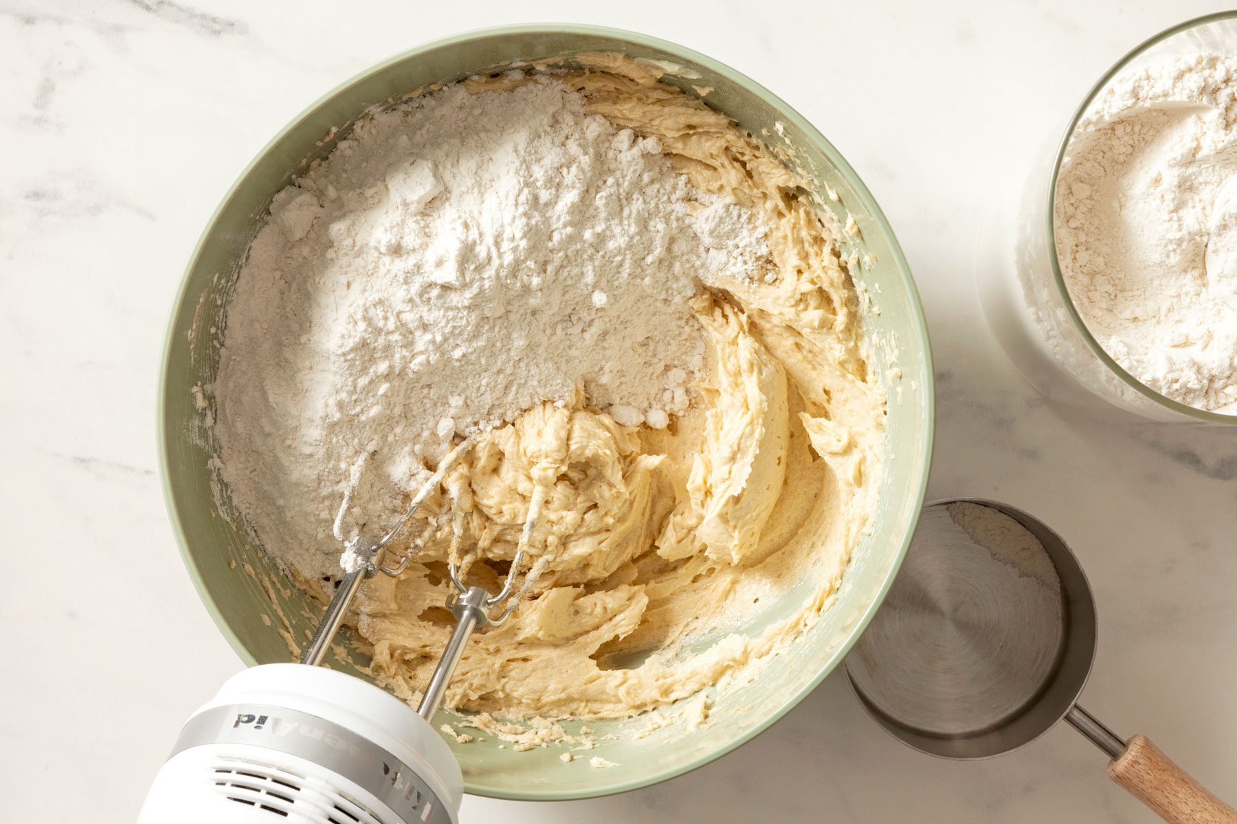 Flour being added to the butter mixture in a large bowl.