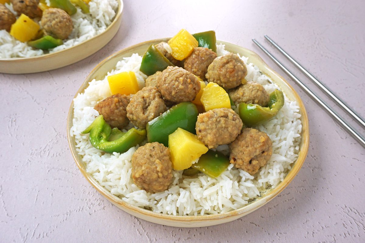 Two plates of slow cooker sweet and sour meatballs with rice and chopsticks for Taste Recipes RMS 27421