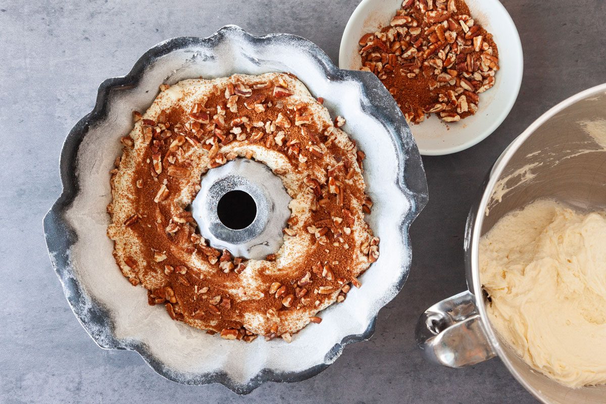 Step 3 of Taste of Home Sour Cream Coffee Cake Bundt is to layer the cake batter and pecan mixtur in a greased and flour bundt pan