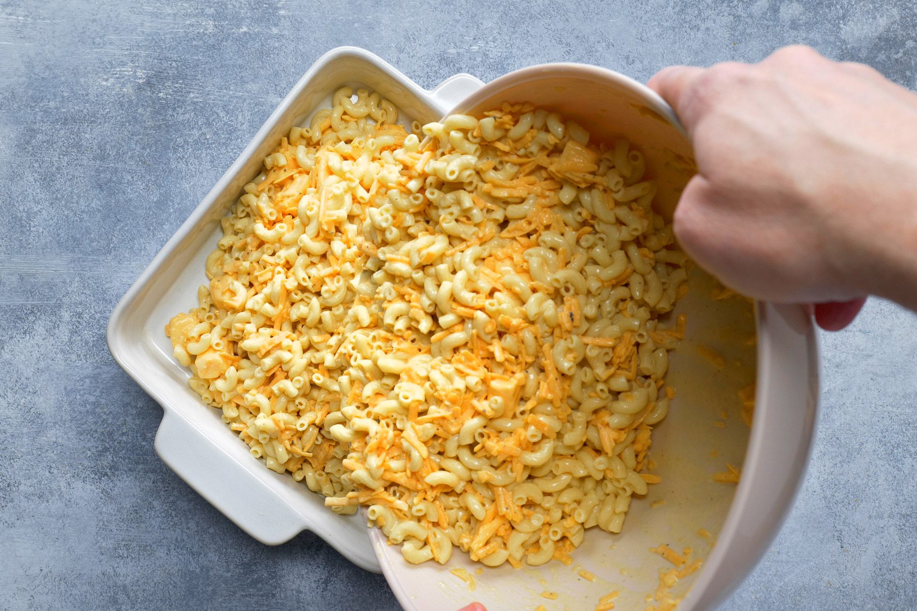 Macaroni and cheese being poured into a greased 3-quart baking dish