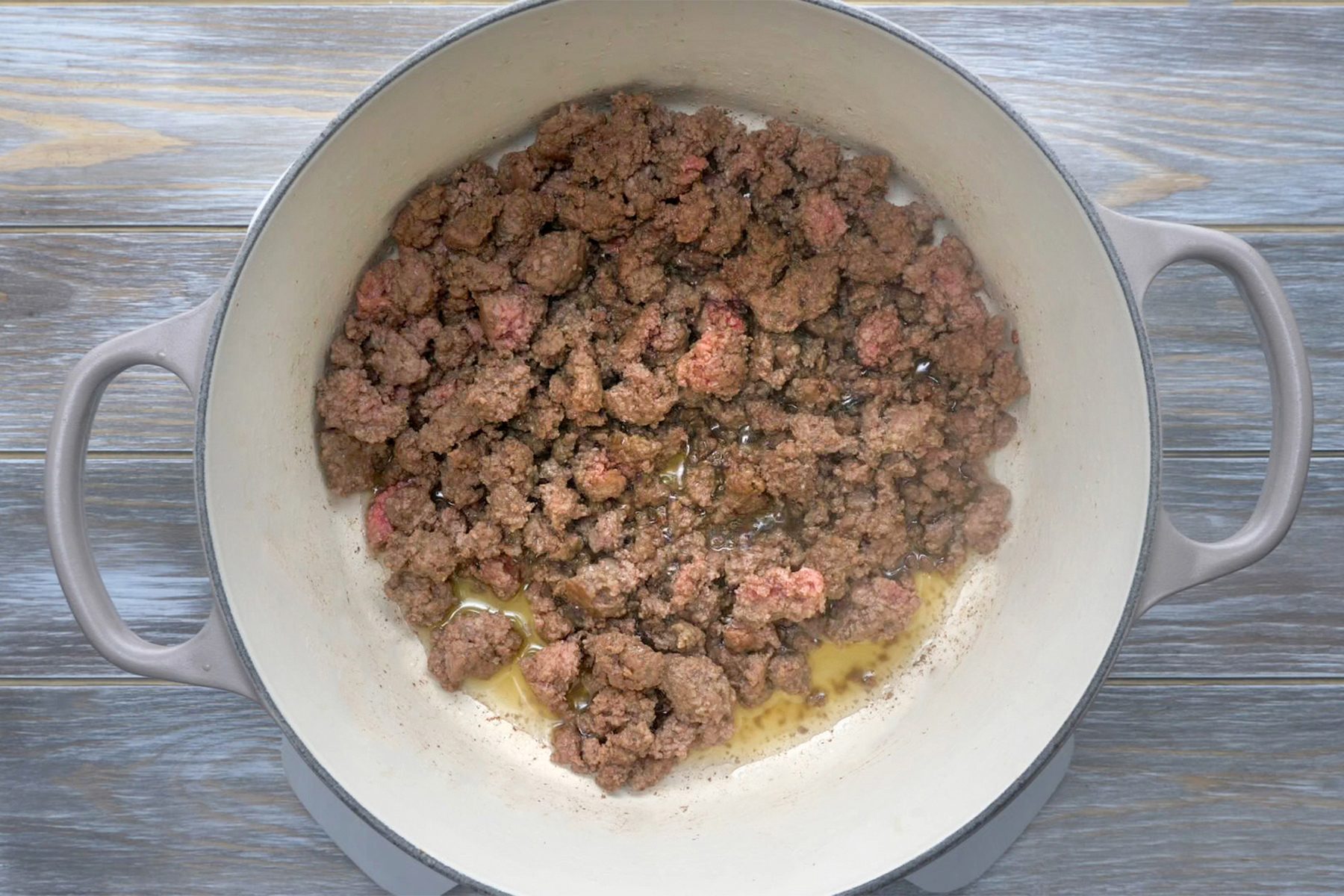 overhead shot; grey wooden background; In a Dutch oven over medium heat, cooking and stiring beef until no longer pink;