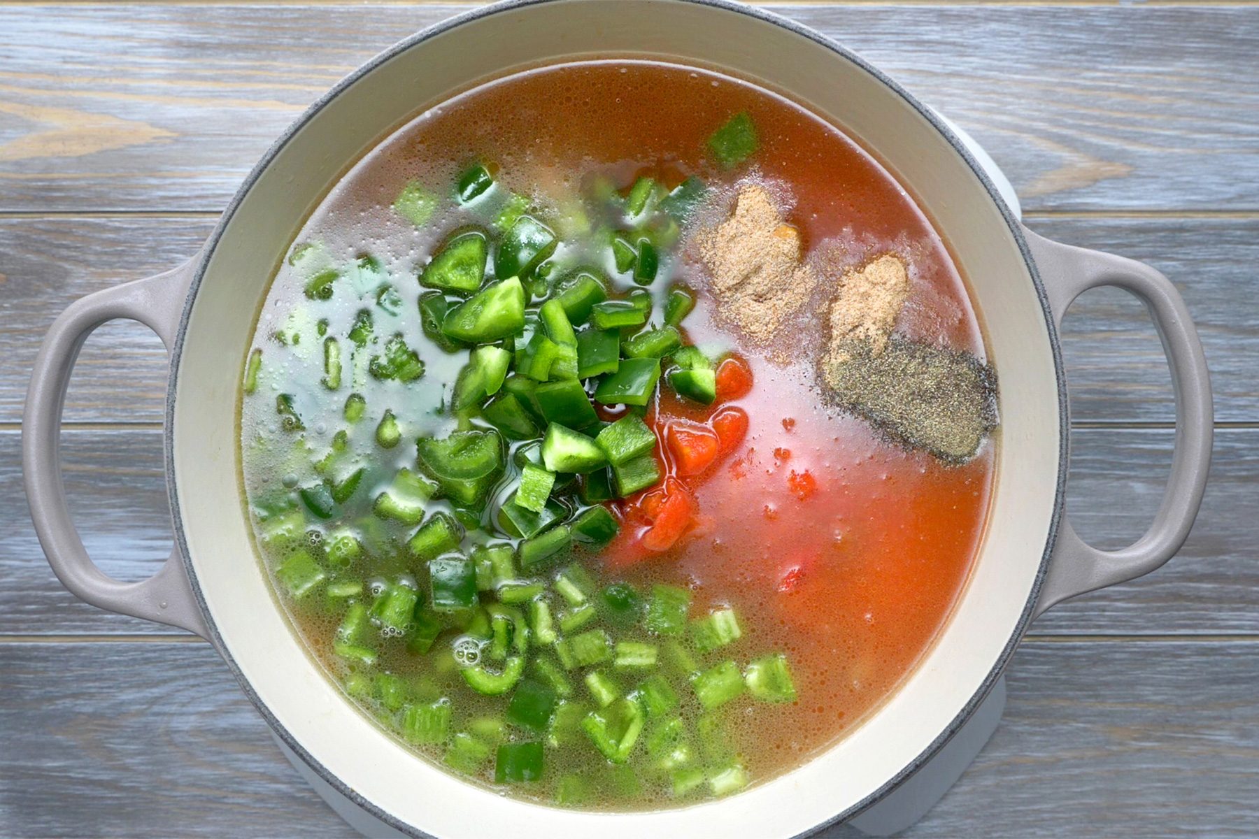 overhead shot; grey wooden background; Stiring in next 8 ingredients; bring to a boil, Reduce heat; simmer, uncovered, until peppers are tender;