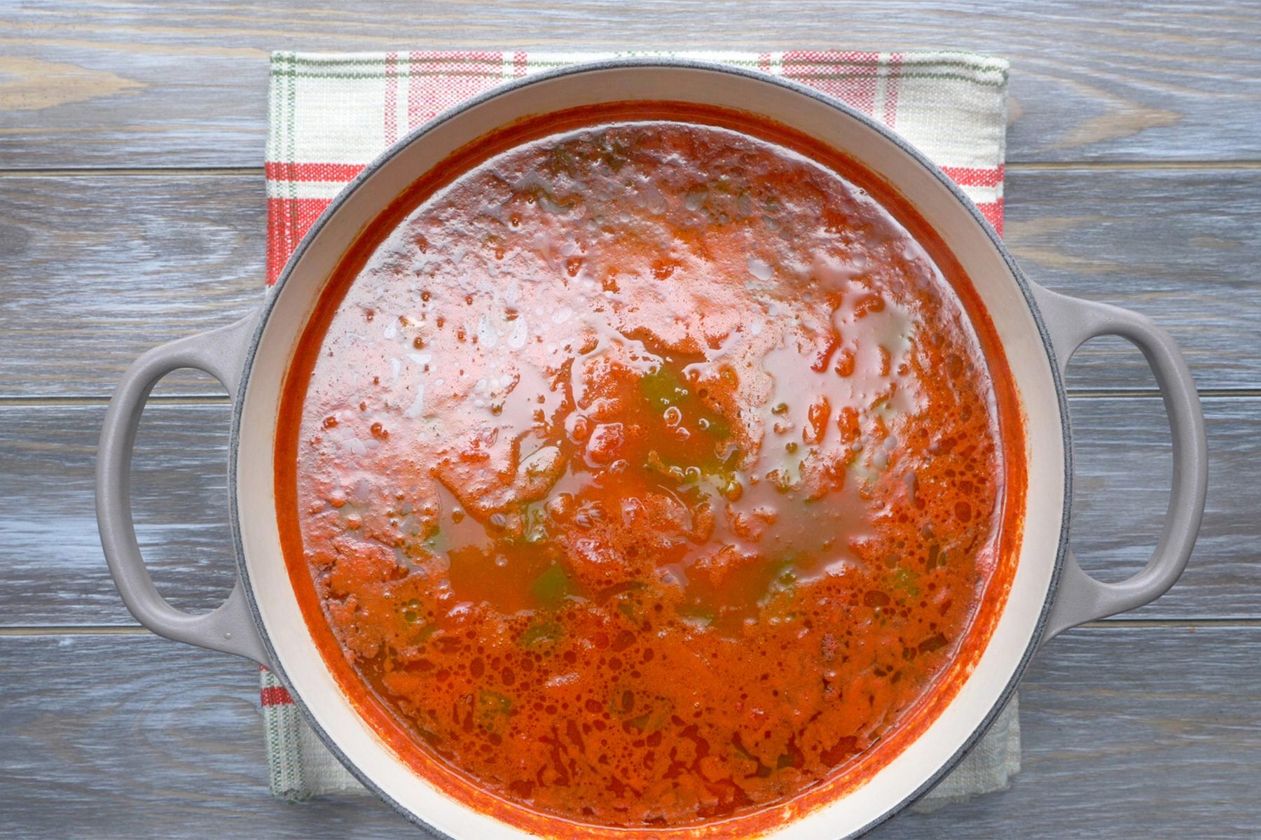 overhead shot; grey wooden background; boiling the mixture in large saucepan;