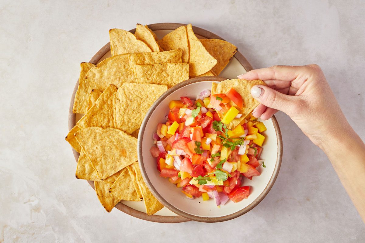 dipping chip in Peach Mango Salsa