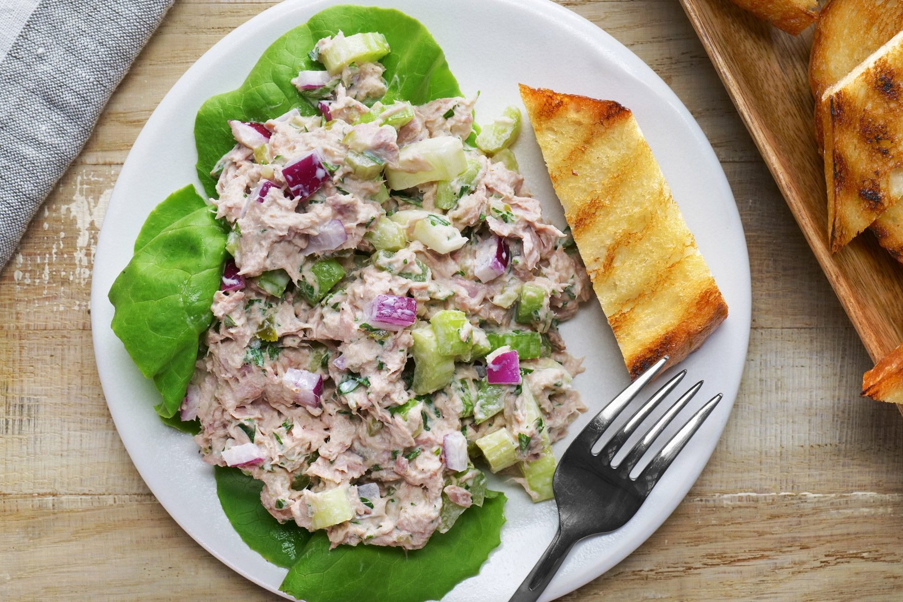 Tuna salad with a fork and a piece of bread on a white plate.