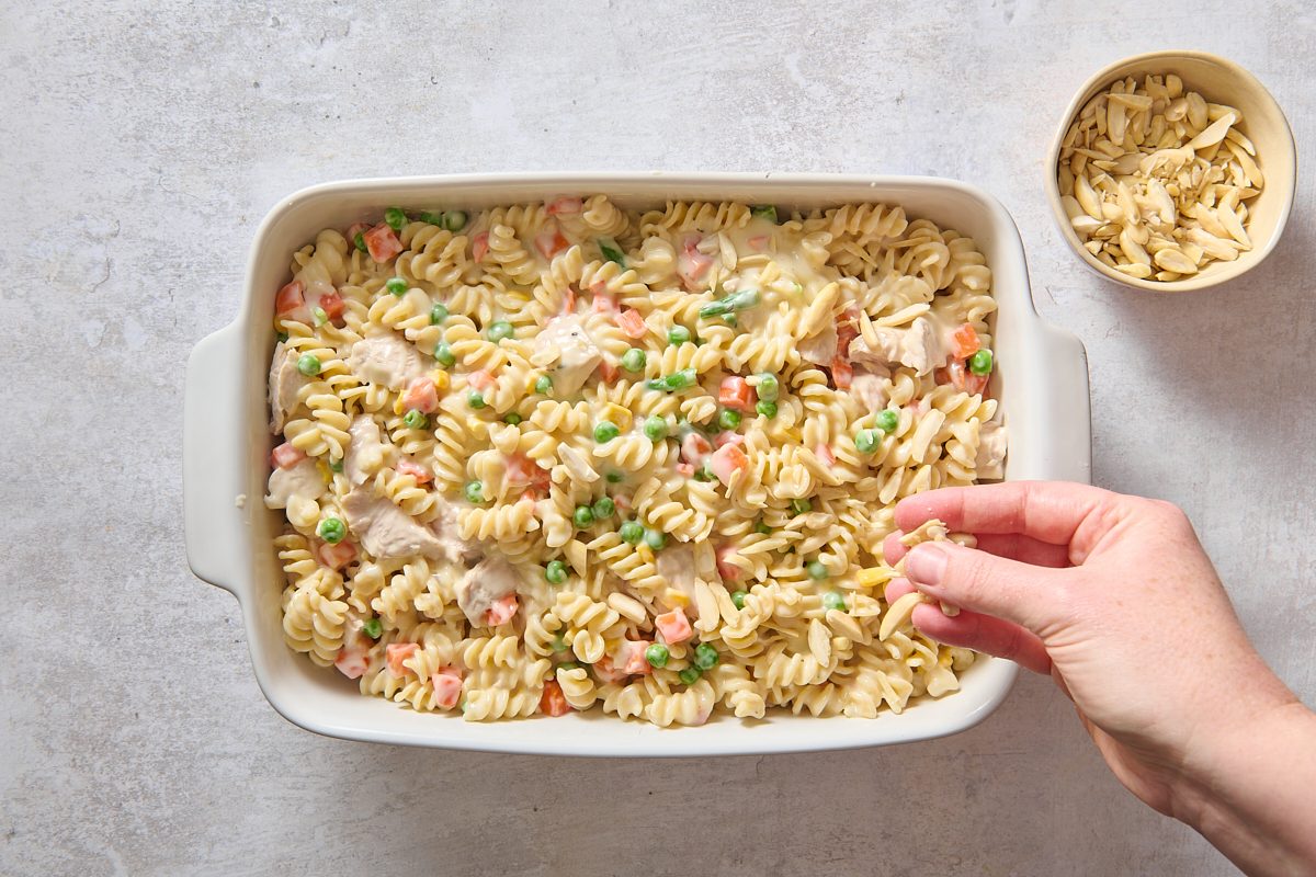 Sprinkling slivered almonds over the casserole in a dish