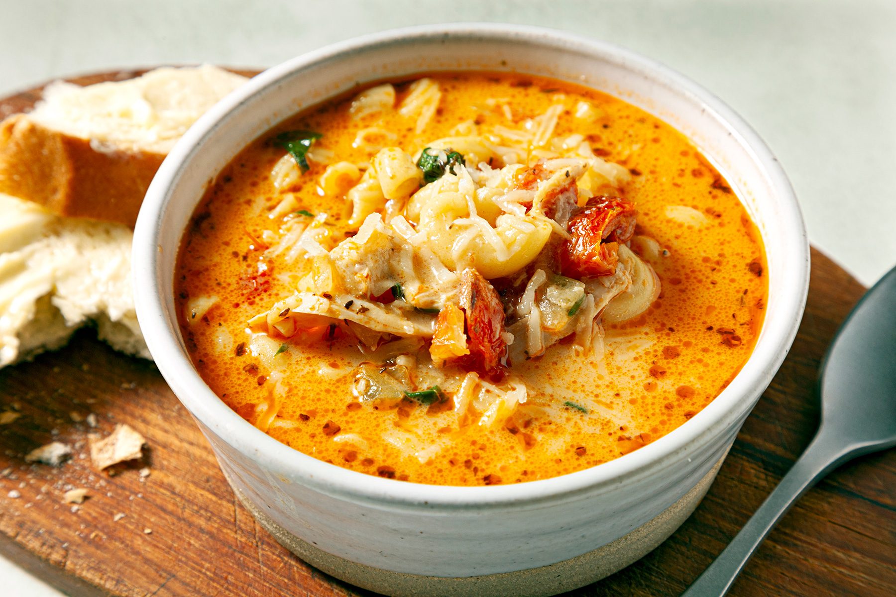 close shot of creamy tuscan chicken soup with shredded cheese