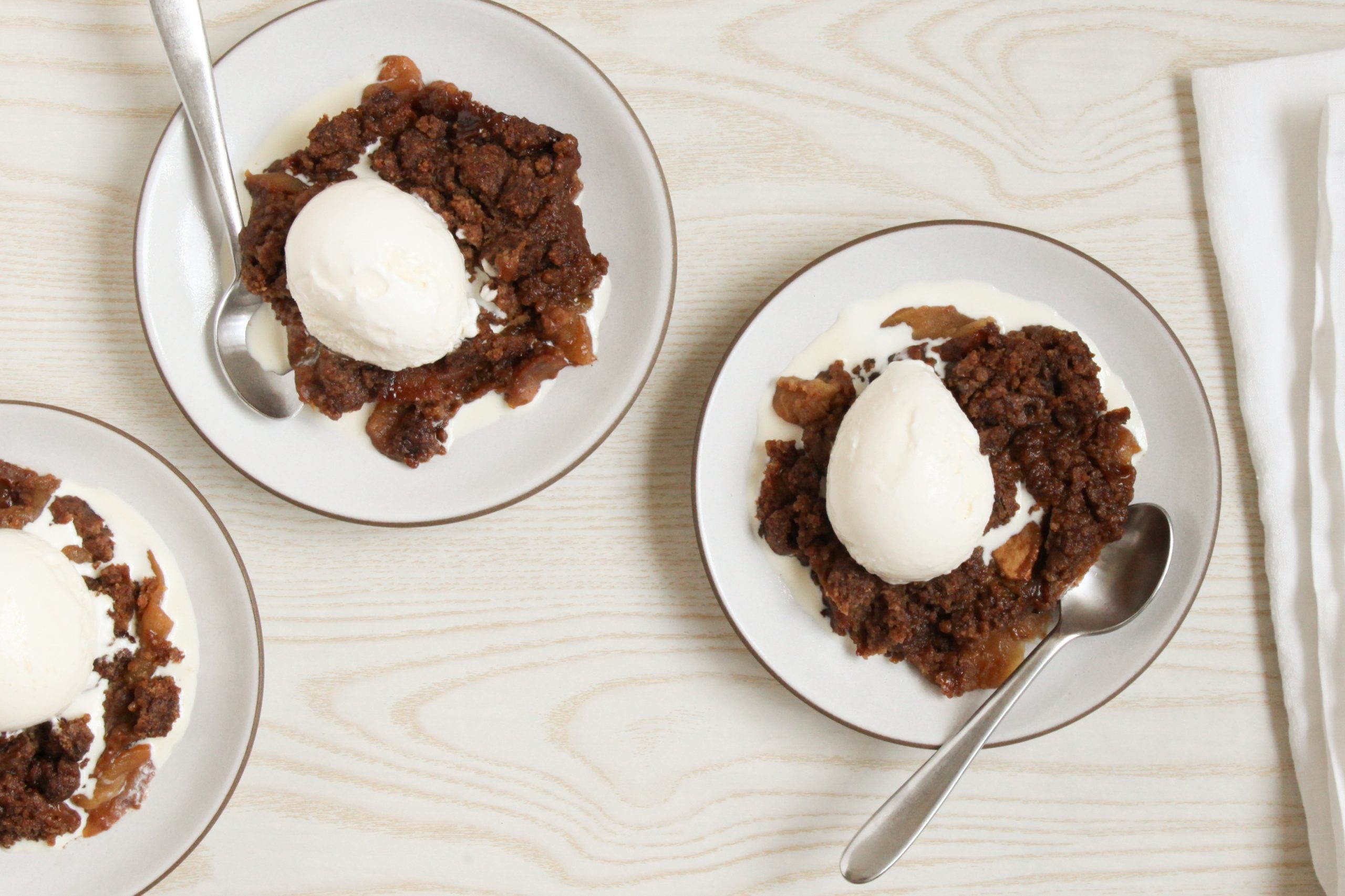 Vegan apple crumble served with vegan vanilla ice cream on plates