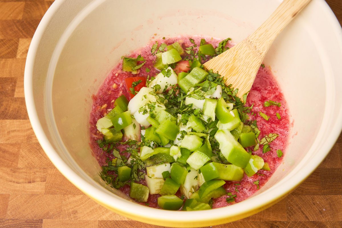 Close up photo of blended watermelon with additional vegetables and seasoning in bowl