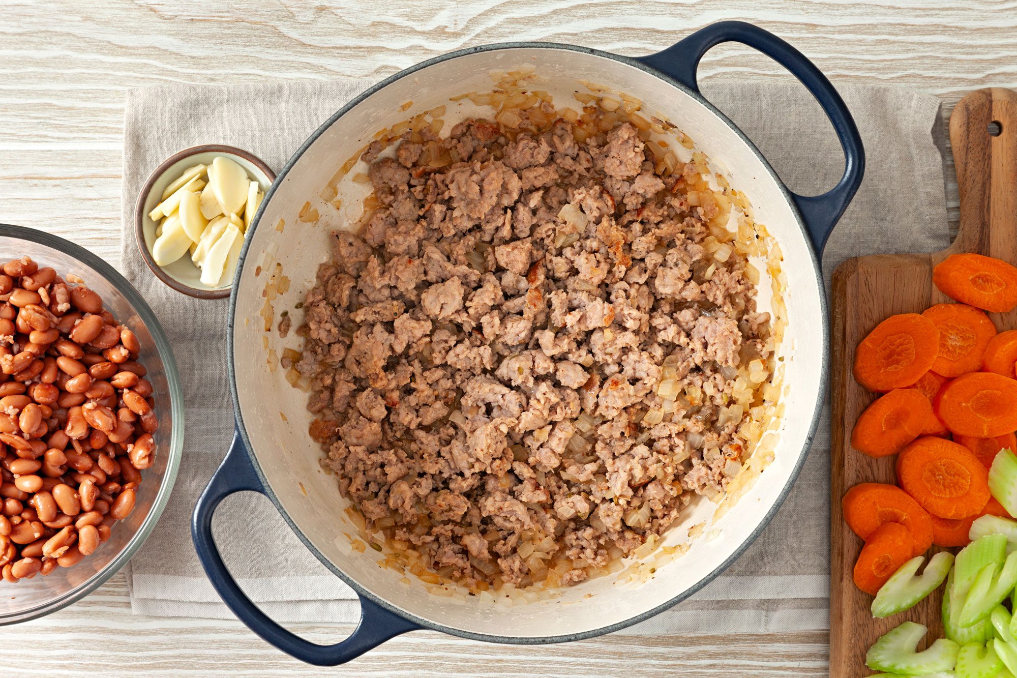 In a Dutch oven, cooking sausage and onion over medium heat until meat is no longer pink; carrot, celery, sage on wooden board