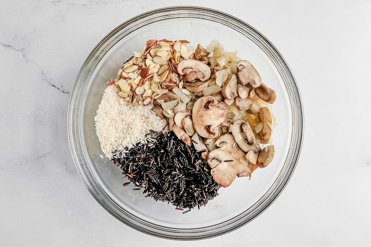 Ingredients for Taste of Home wild rice casserole in a glass bowl on a marble surface.