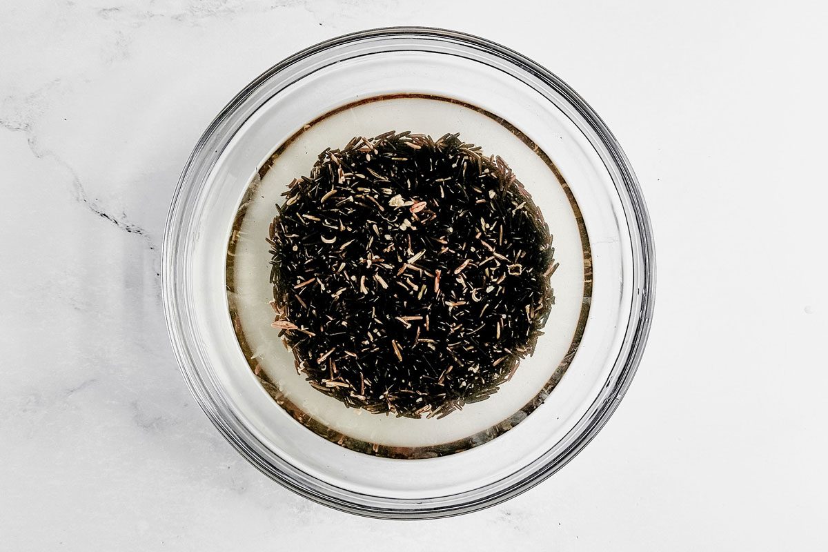 Wild rice for Taste of Home wild rice casserole in a glass bowl on a marble surface.