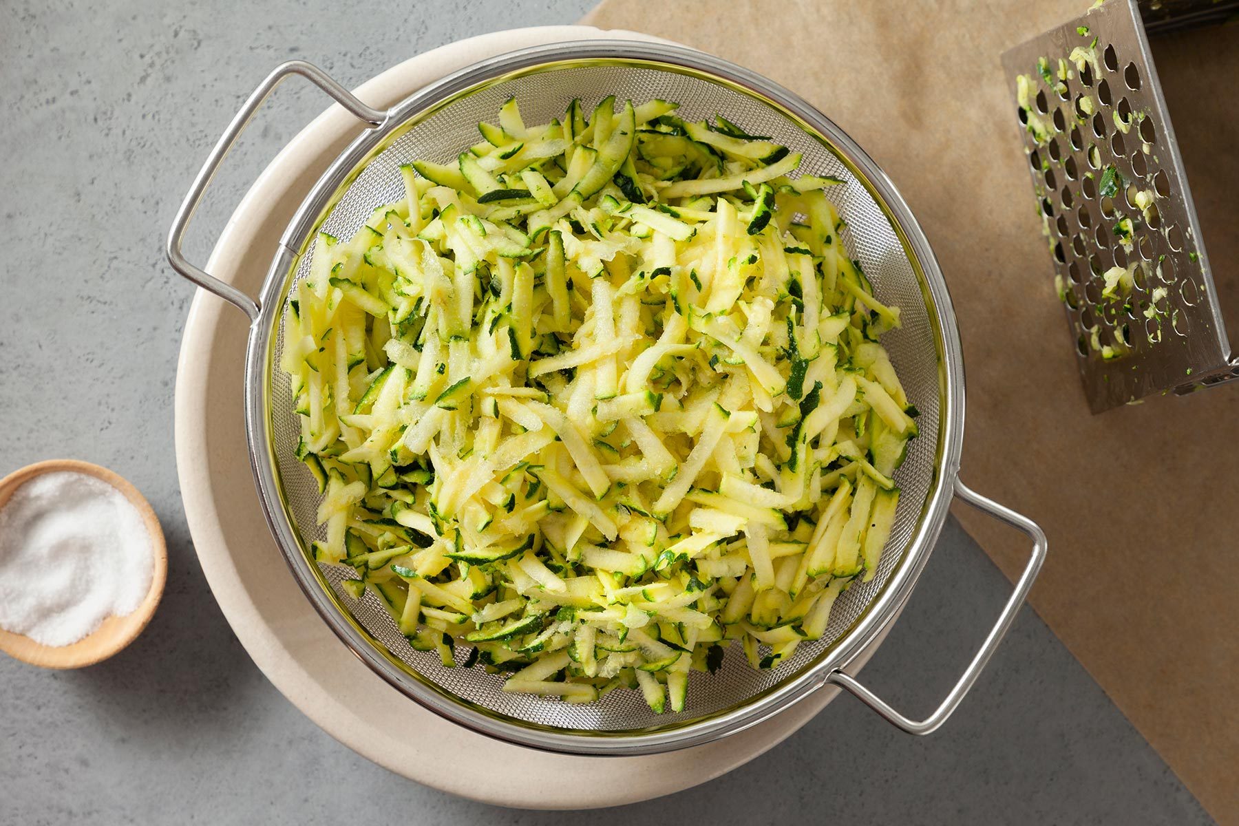 overhead shot of shredded zucchini in a strainer