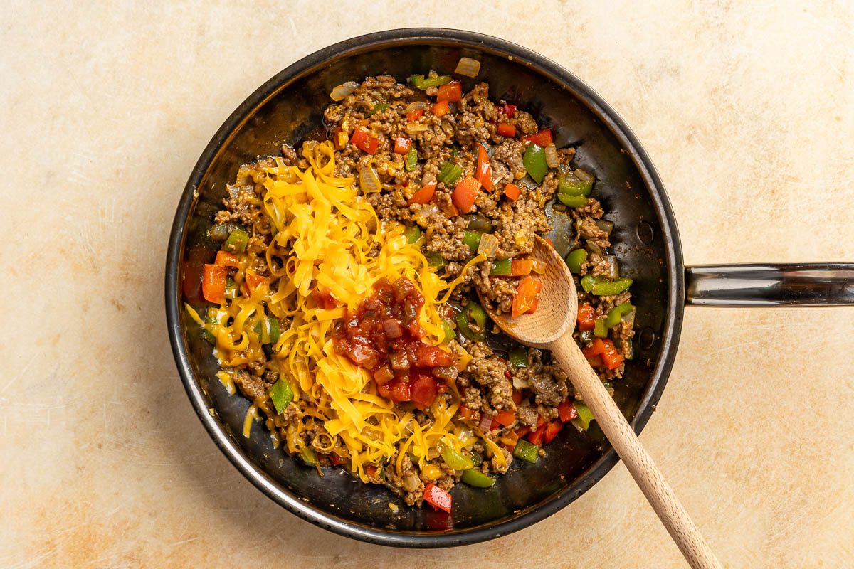 Taste of Home Zucchini Taco Boats recipe photo of the beef, onion, peppers, taco seasoning, garlic, cheddar cheese and salsa cooked in a skillet.