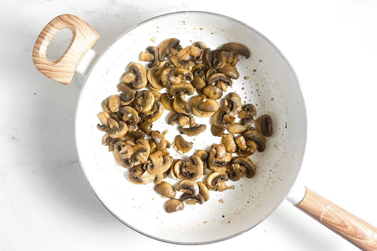 Sauteed mushrooms for Taste of Home Chicken Marsala in a white skillet