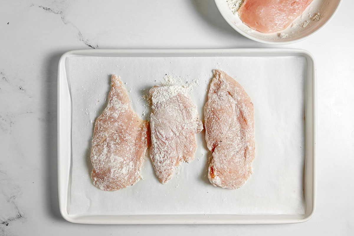 Floured chicken breasts for Taste of Home Chicken Marsala on a baking sheet