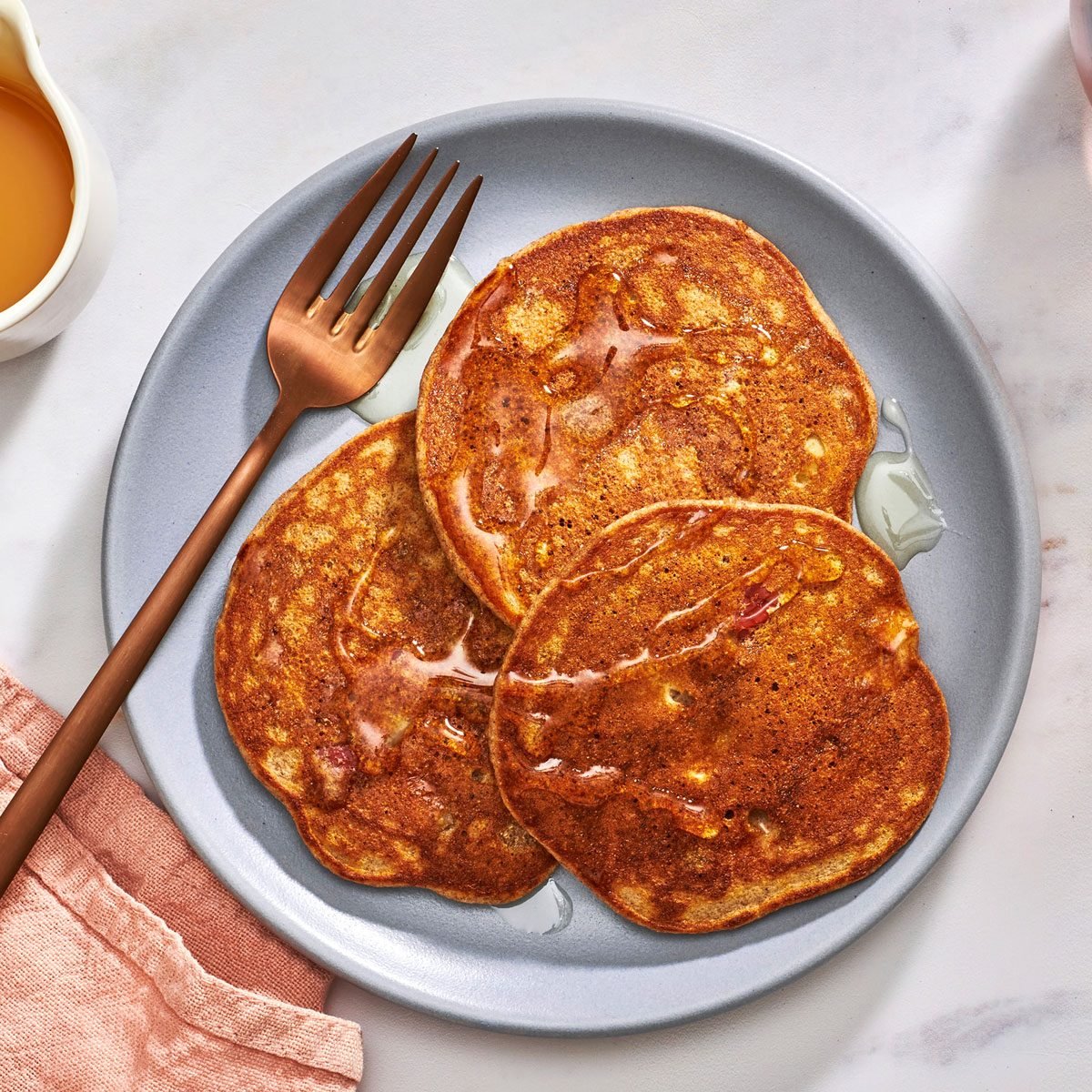 Apple pancakes on a plate drizzled with honey and a fork on the side