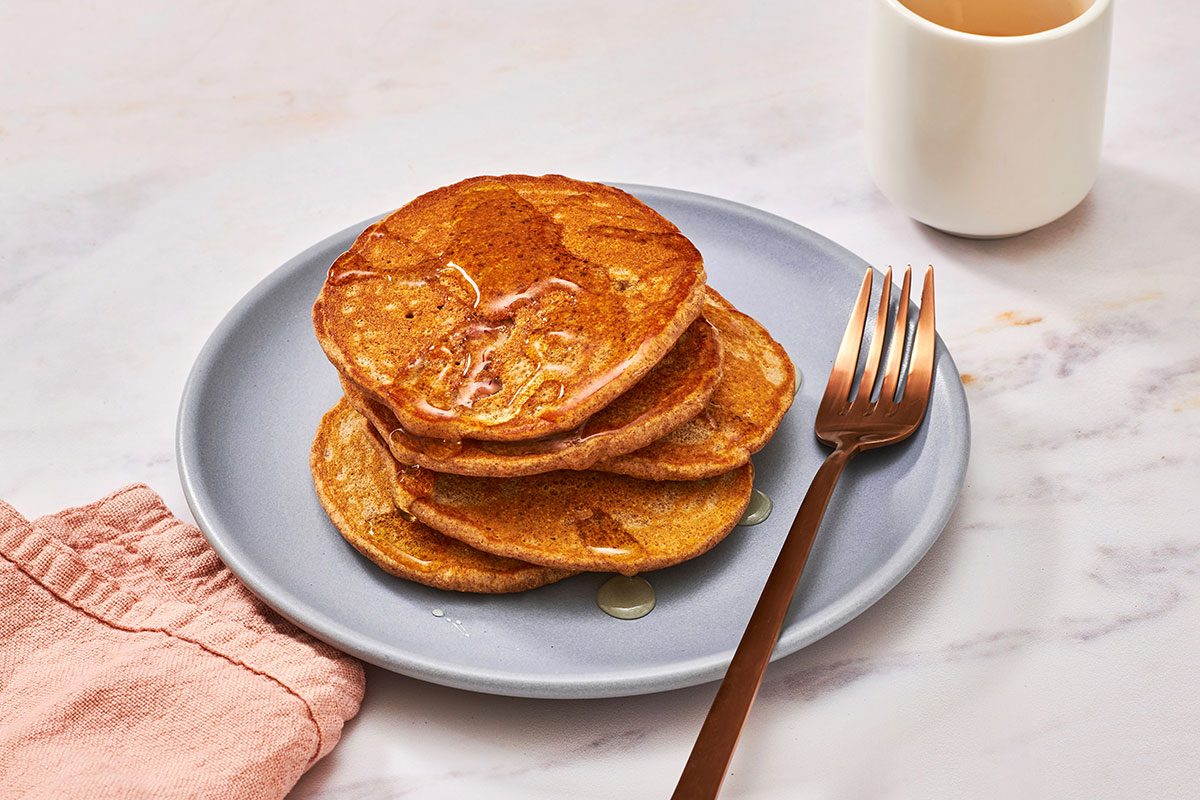 Apple pancakes on a plate drizzled with honey and a fork on the side