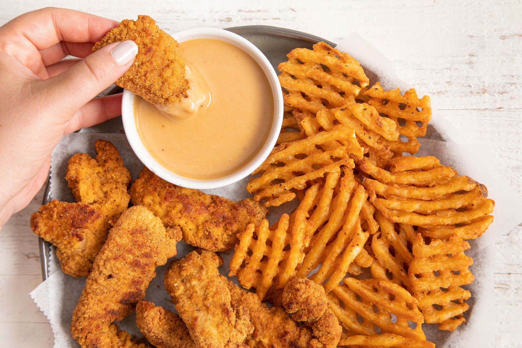 Dipping chicken wings in Copycat Chick Fil A Sauce 