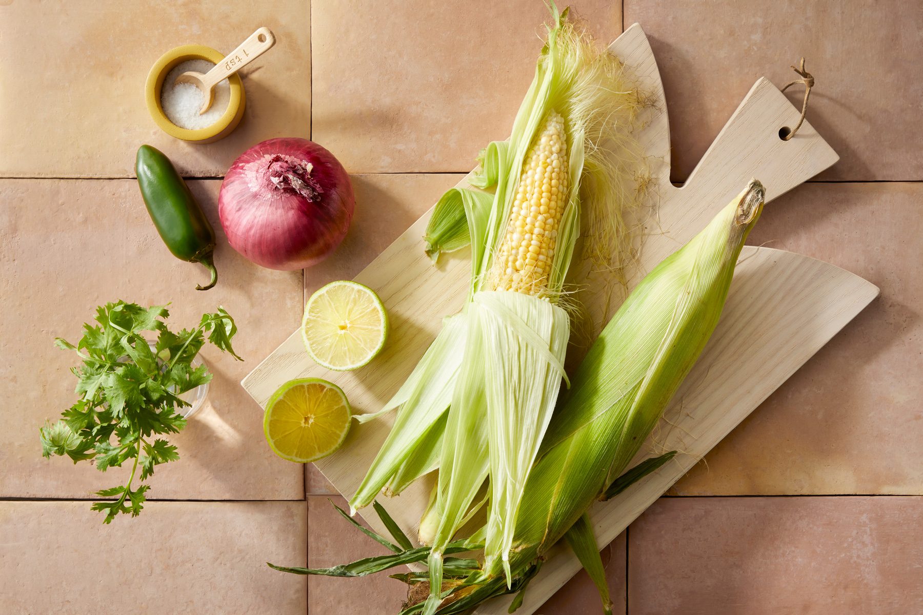 Overhead shot of all ingredients; wooden chopping board; cream square tiles background;