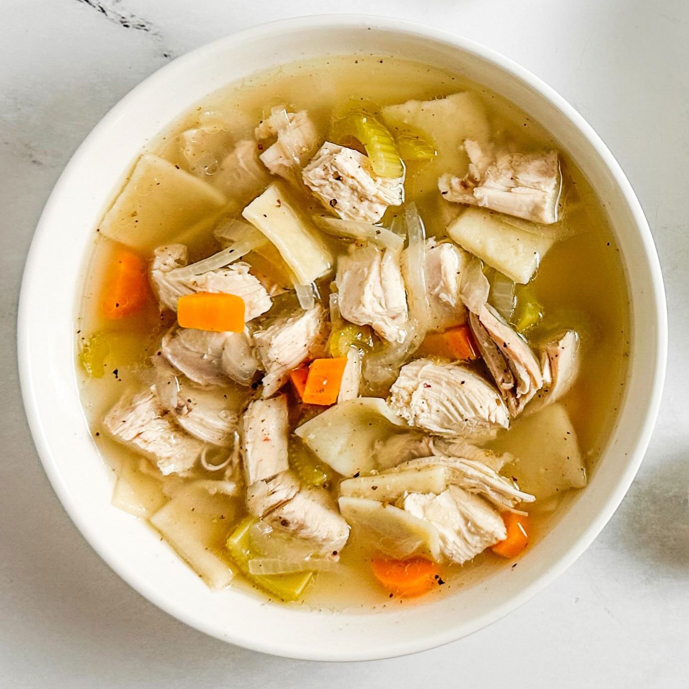 Taste of Home Copycat Cracker Barrel Chicken and Dumplings in white bowls on a marble surface