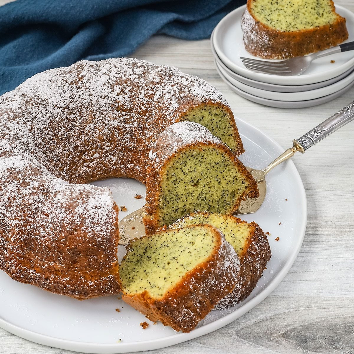 Lemon poppy seed cake is sliced with plates in the background, from a recipe by Taste of Home.