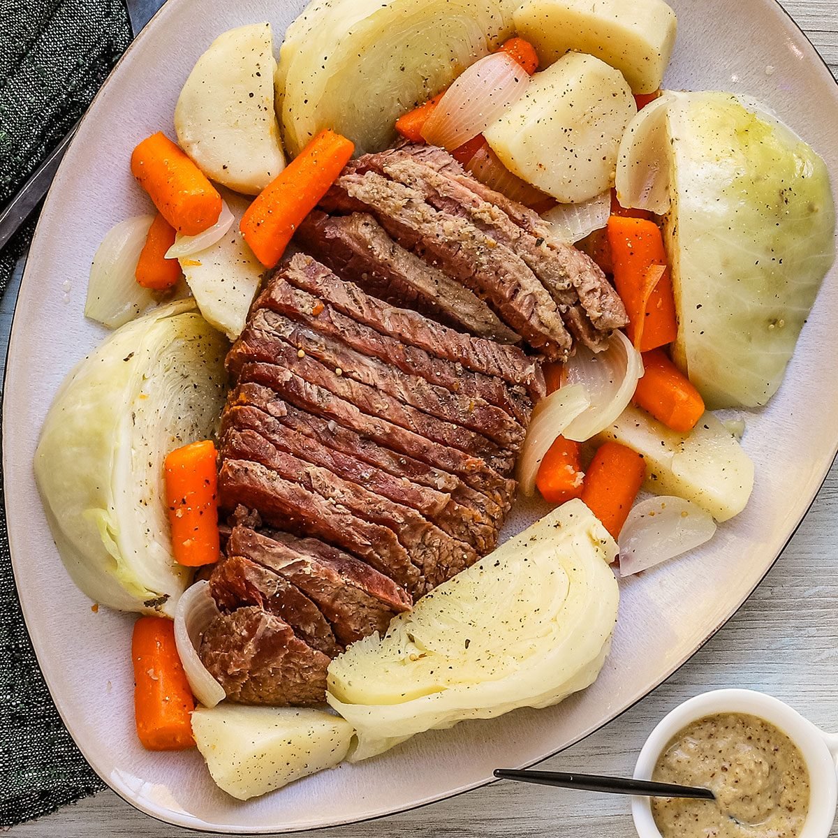 A corned beef boiled dinner with potatoes, carrots, and cabbage, arranged on a large platter.