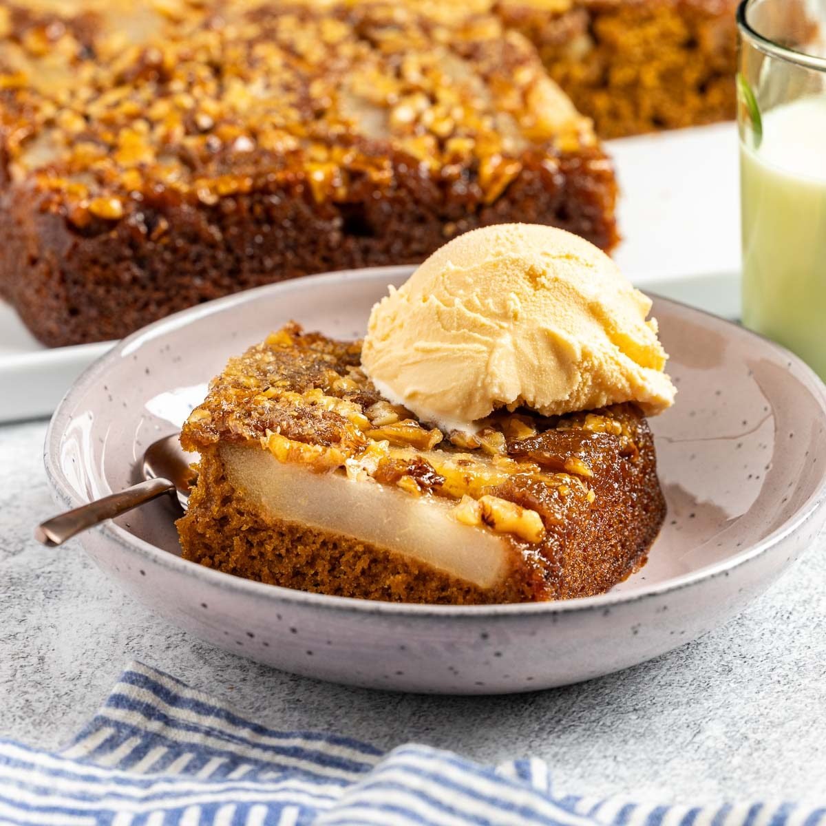 Taste of Home Pear Upside Down Cake recipe photo of the finished cake cute into a slice and topped with ice cream.