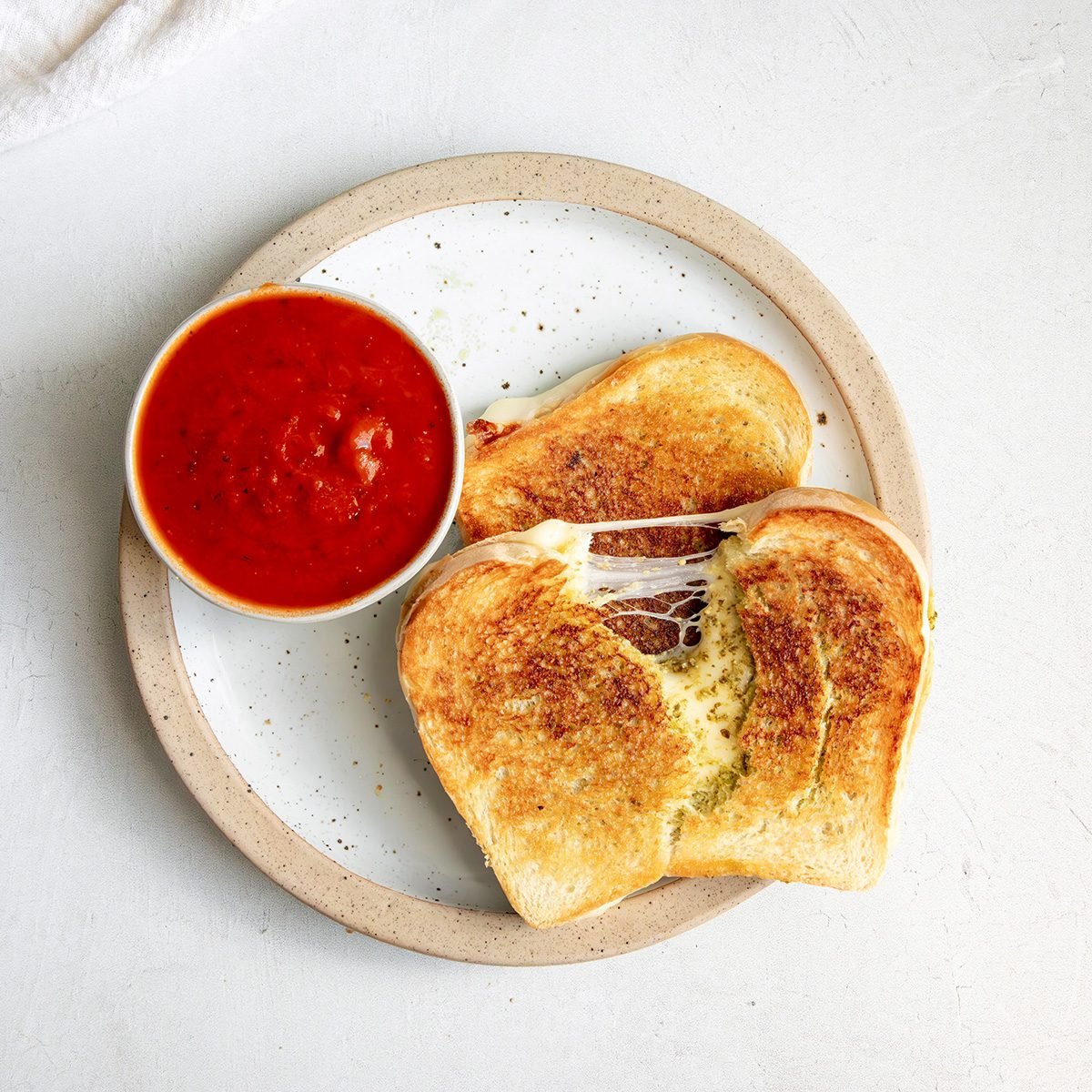 Overhead beauty shot for Taste of Home Pesto Grilled Cheese, sandwich on plate with warmed pizza sauce.