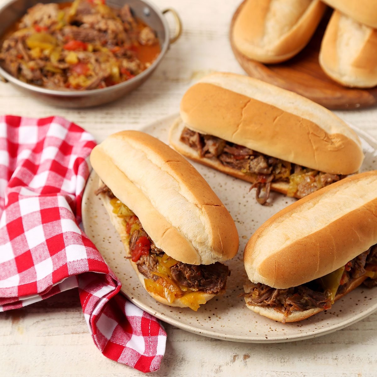 Close up of Taste of Home's Italian Beef Sandwiches served on a platter on a white wooden surface.