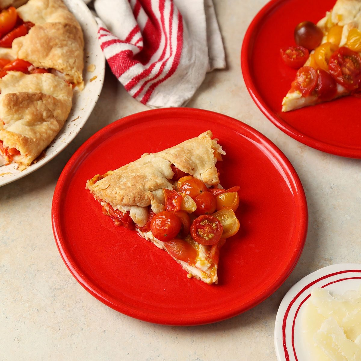 Close up of Taste of Home's Tomato Galette served on a red plate with a beige marble countertop.