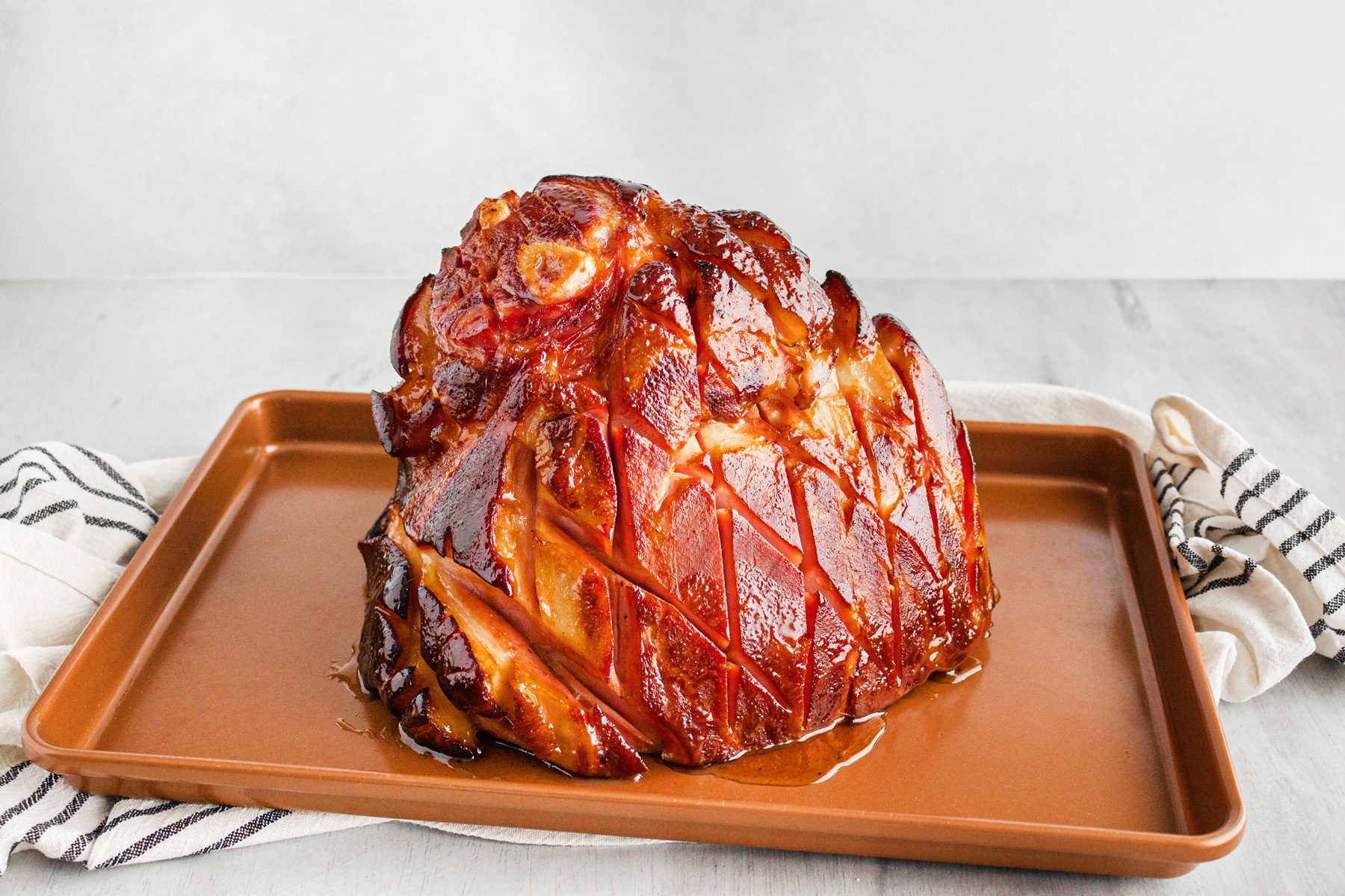 3/4th shot; white background; ham on brown rectangular plate; kitchen towel;